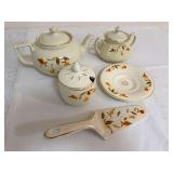 Assortment of Autumn Leaf pieces including large covered teapot, covered two-handled sugar bowl, covered condiment or mustard jar with spoon opening, saucer, and ceramic cake server. The sugar bowl is