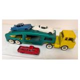 Vintage Structo Auto Haul pressed-steel car carrier with yellow cab and green transport body. Includes three vintage toy vehicles as shown.