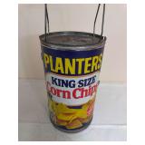 Planters Mr. Peanut outdoor grill fashioned as an oversized Planters King Size Corn Chips can with metal top and wire carrying/support frame. Shows surface wear and oxidation from age and use.