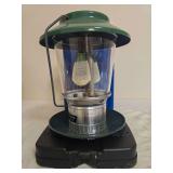 Coleman Model 5114 Propane Lantern with Case. Green portable propane lantern with clear globe, double mantles, wire frame and fitted black carrying base/case; shows general age-related use.