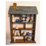 House-shaped wall-mounted wood display shelf with multiple cubbies and assorted ceramic and decorative knickknacks including rabbits, dogs, ducks, owl, Holland figures and brass-tone bell as shown.