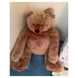 Large plush teddy bear with attached Melissa & Doug tag, accompanied by crib mattress and miscellaneous linens as cataloged.