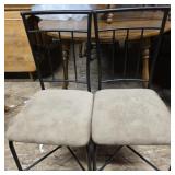 2 black metal chairs with tan upholstered seats