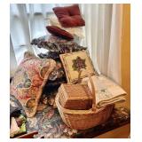 Stack of throw pillows, basket with sewing,