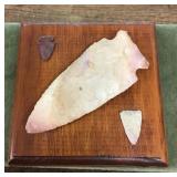 Arrow and spear points mounted on board
