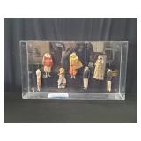 Seven antique cloth doll bodies in a acrylic case