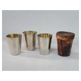 Three vintage steel shot glasses with a leather