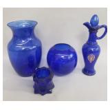 Group of blue glass pitcher, vase, and candle