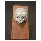 Silver miniature tribal mask mounted on a wood