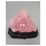Hand carved rose quartz Buddha figure on a wood