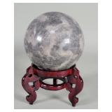 Polished gray and black granite sphere on a wood