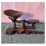 Antique cast iron balance scale with 5 weights.