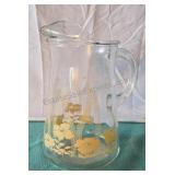 Clear glass juice pitcher with tan floral design.