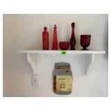 White shelf, red bottles, votives, wall decor sign