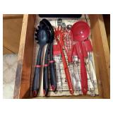 Red, black plastic kitchen utensils, cutting board