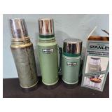three Stanley thermoses