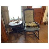 Rocking chair, table, antler, and rug.