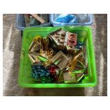 Assorted Gift Wrap, Bows, and Ceramic Bakery Decor in Green Storage Bin