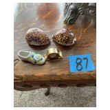 Assorted Decorative Collectibles Including Seashells, Miniature Clock, Porcelain Shoe, Art Glass Bird, and Metal Pitcher