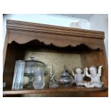 To shelves of miscellaneous glassware a cake