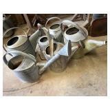 Six old metal watering cans