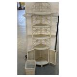 White wicker corner shelf with a waste basket a