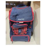 Navy blue and red Easton rolling baseball equipment bag featuring multiple compartments, padded straps, and decorative star pattern accents. Durable wheeled design ideal for transporting sports gear. 