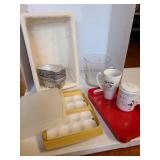 Tupperware deviled egg carrier, porcelain tea mug with lid and infuser on red plastic tray, lined basket, glass pitcher, more