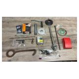 Collection of hardware items including metal fasteners, threaded rods, grinding wheel, metal hook tool, screws, palm sander and more