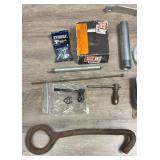 Collection of hardware items including metal fasteners, threaded rods, grinding wheel, metal hook tool, screws, palm sander and more