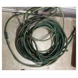 Green garden hoses with a sprayer attached - looks to be close to 50 ft