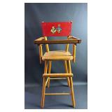 Vintage wood doll high chair, likely an item from the 1950s, featuring a red back panel with a Dutch boy and girl detail. Approximately 27 inches tall and 12 inches wide