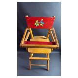 Vintage wood doll high chair, likely an item from the 1950s, featuring a red back panel with a Dutch boy and girl detail. Approximately 27 inches tall and 12 inches wide