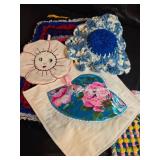 Collection of handcrafted textiles including embroidered linens, crocheted potholders, Rug and More