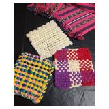 Collection of handcrafted textiles including embroidered linens, crocheted potholders, Rug and More