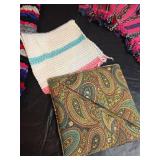 Collection of handcrafted textiles including embroidered linens, crocheted potholders, Rug and More