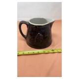 Brown salt, glazed stoneware pitcher has crack on