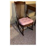 Wooden rocking chair featuring a hand-caned seat