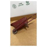 vintage miniature red metal wheelbarrow, likely a