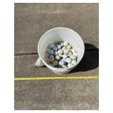 Half full bucket of golf balls and new bag of
