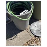 Trashcan with lid full of garden hose