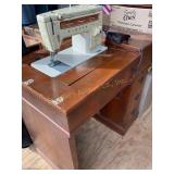Singer sewing machine in wood cabinet (shows wear)