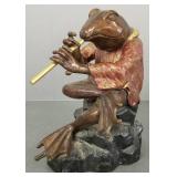 Whimsical bronze frog sculpture playing flute-