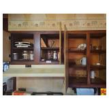 Various kitchen items including jars, a waffle maker, mugs, plates, and other kitchen wares.