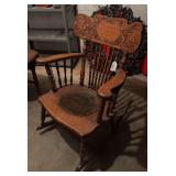 Antique wood rocking chair with carved back, turned wood spindles and worked leather seat.