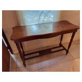 Dark wood console table features classic turned legs and an open lower shelf