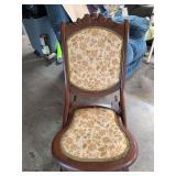 antique or vintage wooden folding rocking chair featuring a carved floral crest at the top and floral tapestry or needlepoint upholstery on the back. Trim needs to be glued down in 2 places.  Very goo