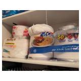 Shelf of paper plates , plastic cups , straws , food storage containers , cook books and plastic Easter tray