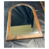 Wood-framed wall mirror with arched top design,