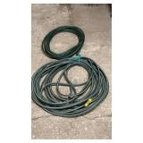 Two green garden hoses, size unknown, coiled and